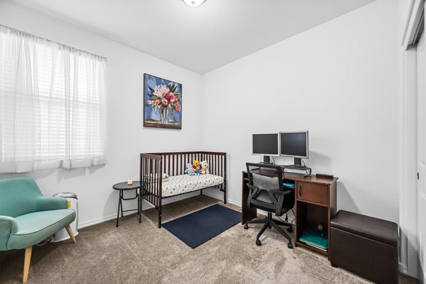 Bright secondary bedroom with soft carpeting, natural light, and versatile space ideal for guests, a nursery, children's room, or a dedicated home office.