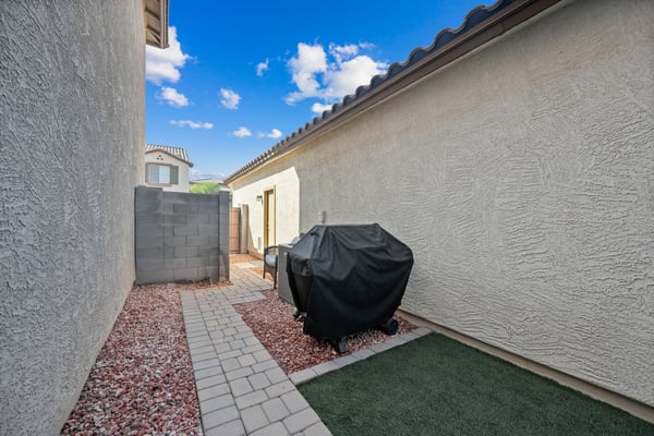 Functional outdoor side yard offering artificial grass, paver pathways, and easy-care landscaping. A practical extension of the home's outdoor living areas in Goodyear.