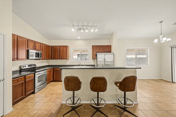 Spacious open kitchen with breakfast bar seating, stainless steel appliances, generous cabinetry, and easy access to the adjoining living and dining spaces.