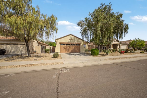 Neighborhood perspective showcasing the home's welcoming setting, mature trees, attractive landscaping, and the peaceful atmosphere of the sought-after Palm Valley community in Goodyear.