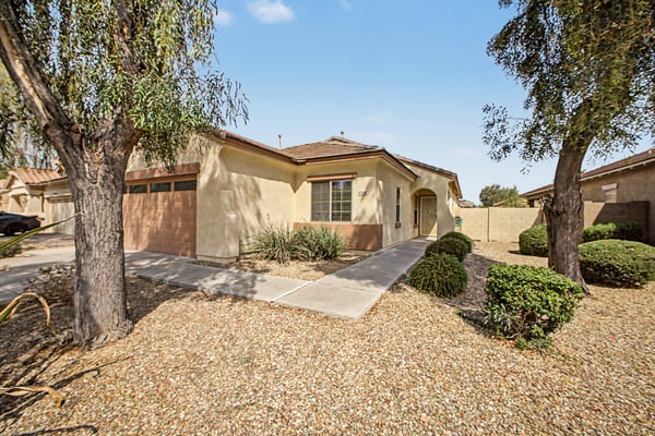 Beautiful front approach featuring a covered entrance, mature landscaping, and low-maintenance desert design that welcomes you home with style and convenience.