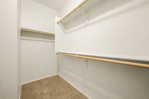 Large walk-in closet featuring multiple hanging rods and generous storage space, helping keep the primary suite organized and clutter-free.