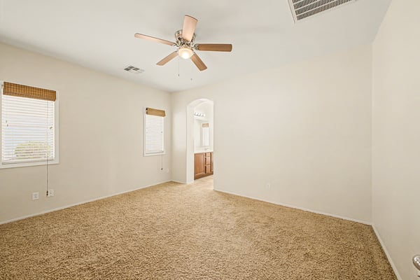 Relaxing owner's suite with plush carpet, ceiling fan, generous dimensions, and direct access to the private ensuite, creating a welcoming retreat in Goodyear.