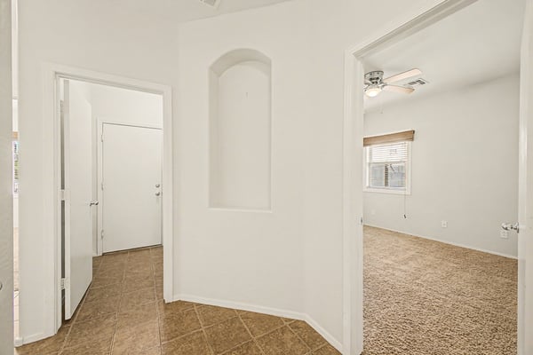Elegant hallway leading to the primary bathroom, showcasing tile flooring, arched entryways, and decorative architectural details.