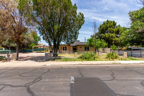 A full view of the property showcases the oversized lot, mature landscaping, covered parking, and generous front yard. Buyers will appreciate the outdoor space, curb appeal, and convenient Mesa location.