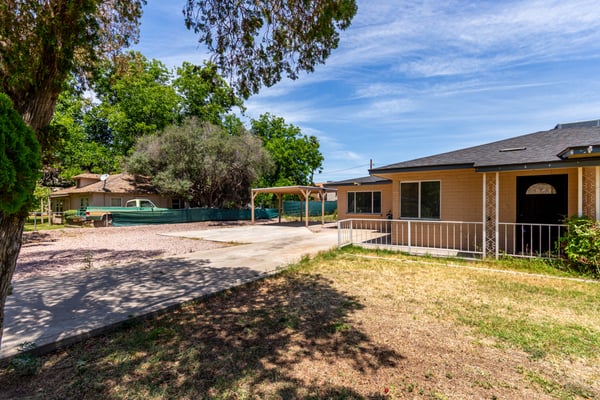 This alternate angle highlights the opposite side of the front yard, featuring lush green space, mature shade trees, and the inviting exterior of the home. The oversized lot provides plenty of room to enjoy outdoor living while maintaining excellent curb appeal.