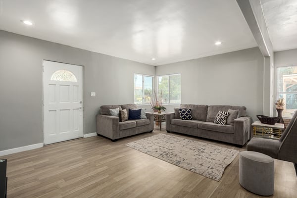 Natural light fills this spacious living room, showcasing updated wood-look flooring, recessed lighting, and neutral finishes throughout. The open, move-in-ready design creates a warm and comfortable gathering space for family and guests.