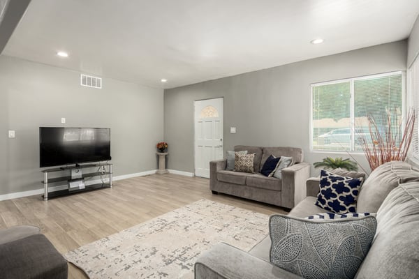 Another view of the open living area highlights the expansive layout, modern flooring, recessed lighting, and bright windows. This remodeled space offers flexible furniture arrangements and a seamless flow for comfortable everyday living and entertaining.