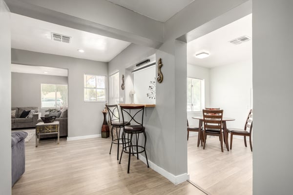 This angle showcases the breakfast bar, open hallway, and seamless connection between the living spaces and kitchen. Bright finishes and updated flooring create a welcoming flow throughout this remodeled Mesa home.