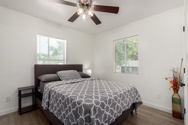 This secondary bedroom features updated flooring, multiple windows, a ceiling fan, and neutral finishes for a bright, comfortable living space. Its versatile design is perfect for guests, family, or a home office.
