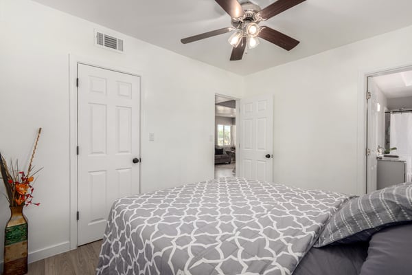Relax in the spacious primary bedroom featuring updated flooring, ceiling fan, large windows, and direct bathroom access. A peaceful retreat that complements the updated interior of this Mesa home.