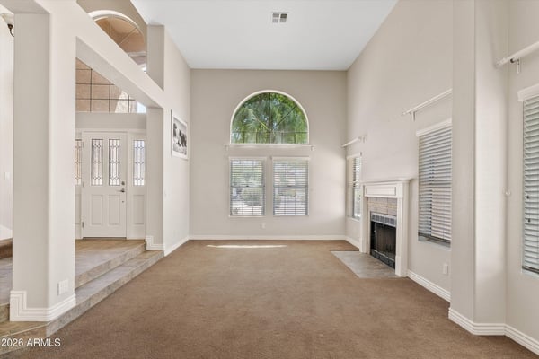 High ceilings, large arched windows, and a charming fireplace make this formal living room bright and welcoming. The spacious layout is ideal for gathering with family or entertaining guests.