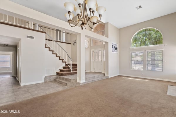 Architectural columns, dramatic ceiling heights, and an elegant staircase create a spacious, open feel throughout the main living area. The layout flows naturally into adjoining rooms for effortless entertaining.