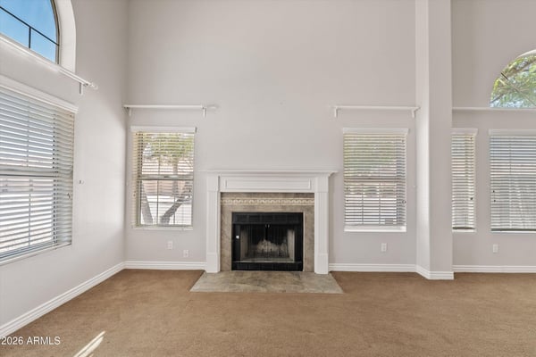 The wood-burning fireplace serves as the centerpiece of this spacious living room, complemented by tall ceilings and large windows that brighten the space. Its warm ambiance makes it the perfect place to gather with family and friends throughout the year.