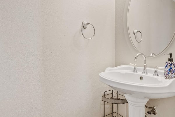 This convenient powder room features a pedestal sink, bright lighting, and neutral finishes, offering both style and functionality for guests and everyday living.