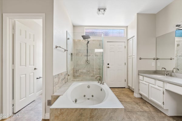 Relax in the spacious primary ensuite featuring a jetted soaking tub, oversized glass shower, updated fixtures, and abundant natural light. Thoughtfully designed for everyday comfort and luxury in Chandler.