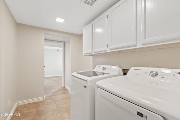 This well-appointed laundry room includes upper cabinetry, modern appliances, and additional storage to simplify daily routines. Conveniently located within the home's practical floor plan.