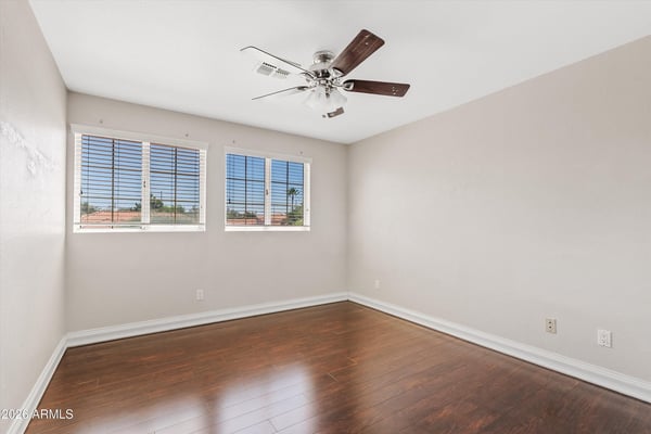 Rich wood flooring, large windows, ceiling fan, and neutral finishes make this spacious bedroom bright, comfortable, and move-in ready for family or guests.