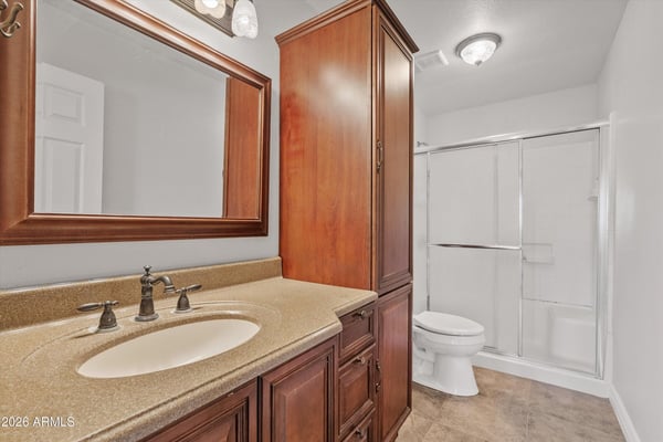 Updated cabinetry, modern fixtures, framed mirror, and a sliding glass shower enclosure create a clean and functional bathroom serving the secondary living spaces.