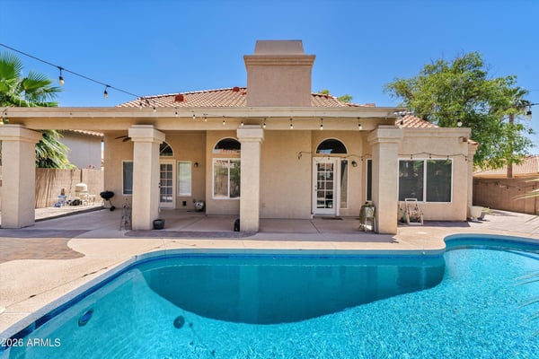 This covered patio overlooks the inviting swimming pool and landscaped backyard, offering comfortable outdoor living with plenty of space for entertaining and relaxing.