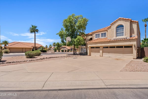 A broad front view highlights the home's attractive architecture, mature landscaping, and expansive driveway. This move-in-ready Chandler home combines timeless style with everyday convenience.
