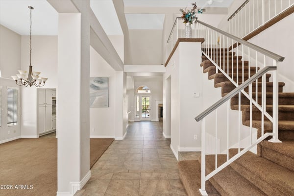A soaring two-story entry welcomes guests with elegant tile flooring, natural light, and a sweeping staircase. The spacious foyer sets the tone for the home's open and inviting floor plan.