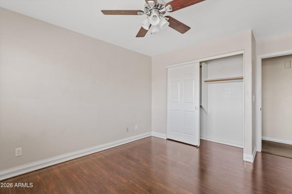 This secondary bedroom features attractive wood flooring, a ceiling fan, ample closet space, and a flexible layout that adapts easily to changing household needs.