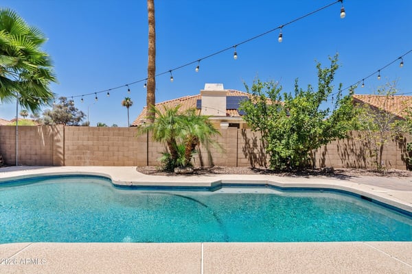 The beautifully maintained backyard features a sparkling pool, mature landscaping, decorative lighting, and privacy, creating an ideal outdoor retreat for everyday enjoyment.