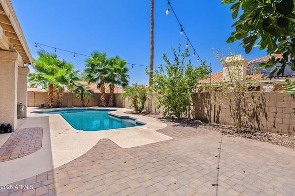 Wide paver patios, lush landscaping, and a sparkling pool create a welcoming outdoor space for gatherings, dining, and enjoying Arizona's beautiful weather in Chandler.