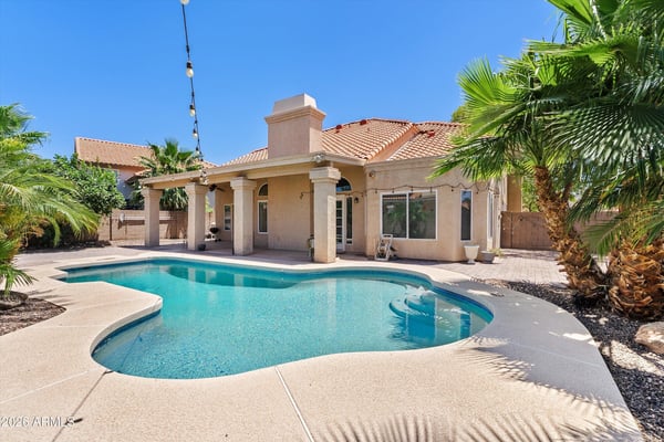 Enjoy resort-style outdoor living with a sparkling swimming pool, covered patio, mature tropical landscaping, and inviting entertaining spaces. This Chandler backyard is designed for relaxing and gathering year-round.