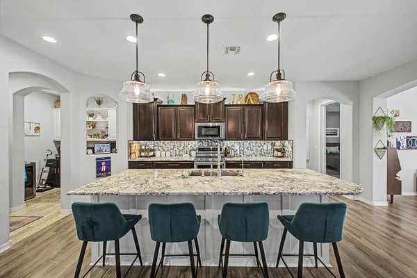 Oversized granite island with breakfast seating anchors this upgraded kitchen featuring custom cabinetry, pendant lighting, and an open layout ideal for entertaining and everyday family living.