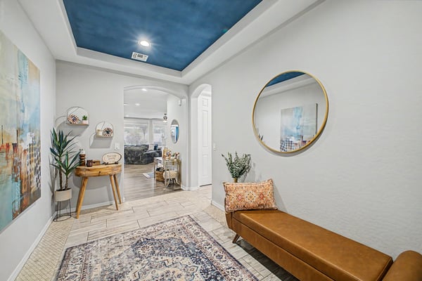 Welcoming foyer featuring a custom wood front door, tray ceiling, upgraded tile flooring, and stylish finishes that create an elegant entrance into this beautifully designed home.