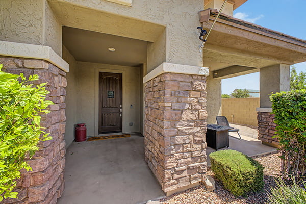 Covered front entry features stone accents, a custom wood front door, and a relaxing porch that welcomes guests while adding timeless character to this beautifully maintained home.