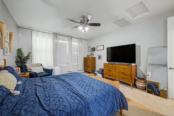 This alternate view of the primary bedroom showcases its spacious layout, natural light, ceiling fan, and flexible arrangement for oversized furniture.