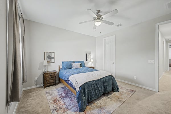 This bright secondary bedroom showcases generous dimensions, soft carpeting, ceiling fan, and flexible space suitable for guests, family members, or a home office.