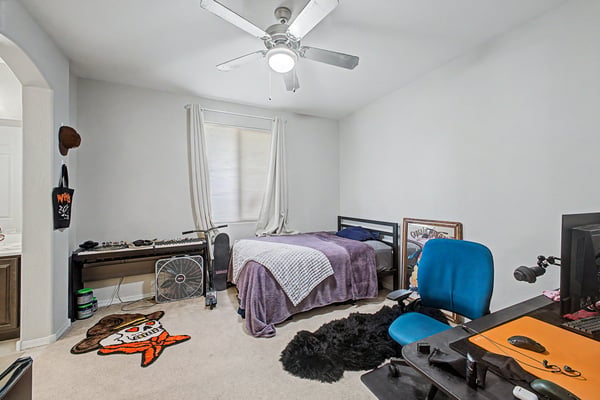 Spacious bedroom includes plush carpeting, ceiling fan, and natural light, offering flexibility for sleeping, working, or creating a personalized living space.