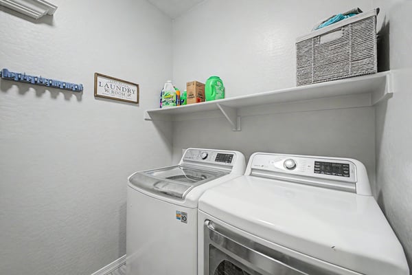 Laundry room offers modern appliances, convenient storage shelf, and efficient organization to simplify daily household tasks while maximizing functionality.