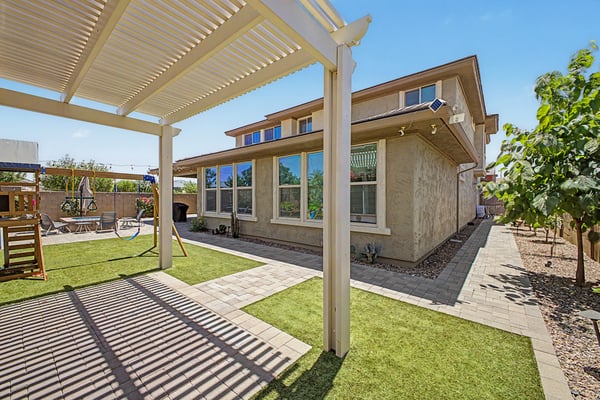 Alternate perspective highlights the spacious backyard with pergola, paver walkways, artificial lawn, and attractive landscaping that complements the home's outdoor amenities.