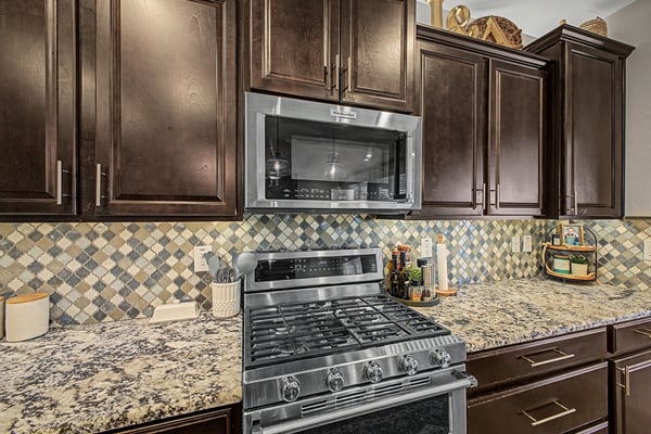 Elegant finishes include granite countertops, decorative backsplash, stainless steel appliances, gas cooking, and extensive cabinetry that combine beauty with everyday functionality.