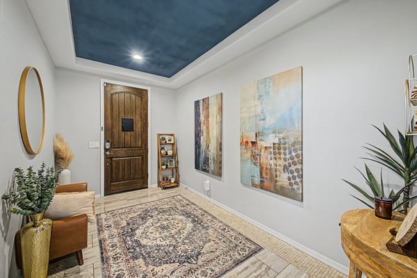Beautiful foyer showcasing upgraded finishes, decorative tray ceiling, custom wood entry door, and a spacious layout that immediately welcomes family and guests.