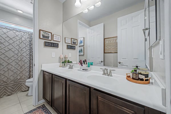 Shared bathroom features a dual-sink vanity, spacious countertops, modern cabinetry, and quality finishes that enhance everyday functionality.