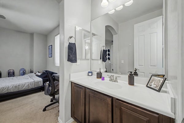 Alternate view of the private bathroom highlights the oversized vanity, abundant countertop space, modern fixtures, and functional design for everyday living.