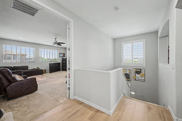 Open landing provides seamless flow between the upper-level living spaces while showcasing natural light, neutral finishes, and an inviting layout throughout the home.