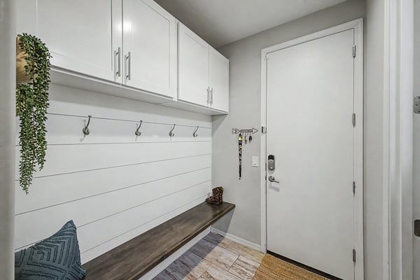 Functional entryway features custom built-in storage, bench seating, coat hooks, and upper cabinets, providing an attractive and organized everyday entry.