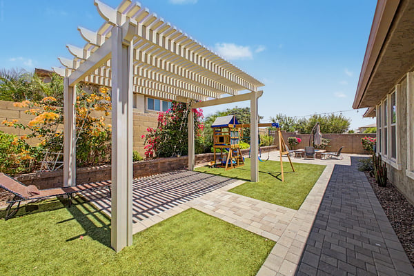 Backyard retreat features lush landscaping, pergola, artificial turf, and generous open space, creating an inviting environment for recreation and outdoor entertaining.