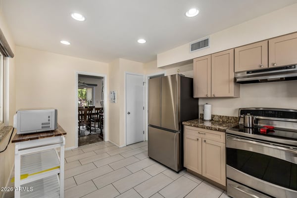 Clean and efficient kitchen featuring updated cabinetry, granite countertops, stainless steel appliances, tile flooring, and excellent storage for everyday convenience.