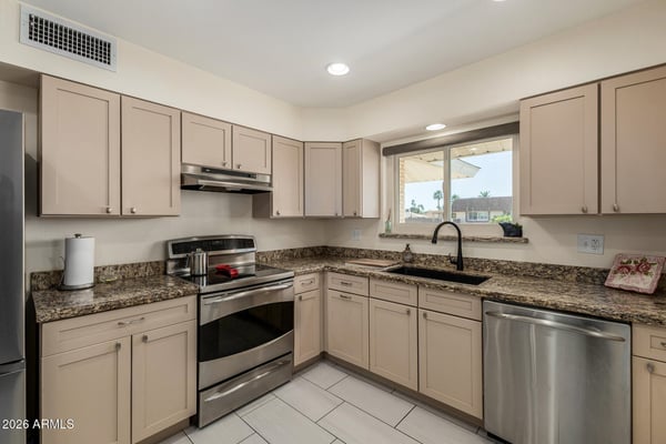 Spacious kitchen with expansive granite countertops, modern cabinetry, stainless steel appliances, recessed lighting, and a backyard-facing window that fills the room with natural light.