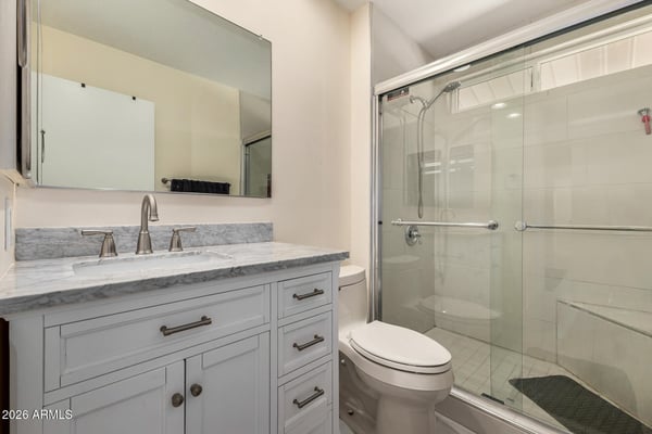 Stylish bathroom showcasing a walk-in glass shower, marble-look countertop, updated vanity cabinetry, and contemporary fixtures designed for comfort and convenience.