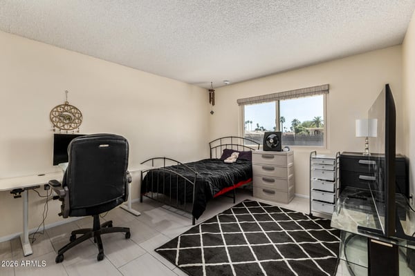 Bright bedroom with room for sleeping, working, or studying, featuring tile flooring, generous natural light, and a comfortable layout.