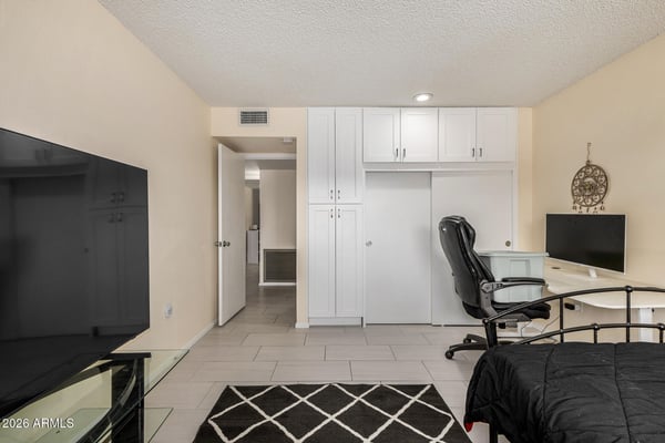 Flexible bedroom offering dedicated workspace potential, built-in storage, tile flooring, and ample room for guests or remote work.